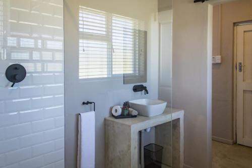 a white bathroom with a sink and a window at Brinkley's River Village in Klein Brak Rivier