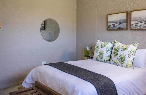 a bedroom with a large white bed with a mirror at Brinkley's River Village in Klein Brak Rivier