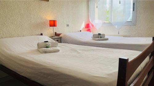 2 Betten in einem Schlafzimmer mit Handtüchern und einem Fenster in der Unterkunft La Coccinelle YourHostHelper in Gujan-Mestras
