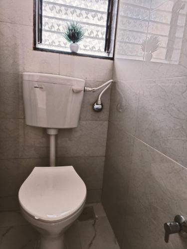 bagno con servizi igienici bianchi e finestra di Great Hornbill Homestay, Ratnagiri a Ratnagiri