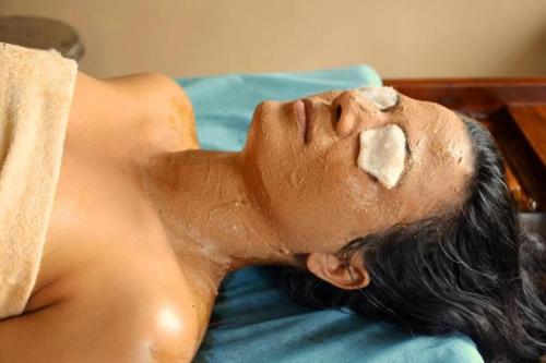 un hombre acostado en una cama con barro en su cara en Ayurveda Bhavan en Rishīkesh