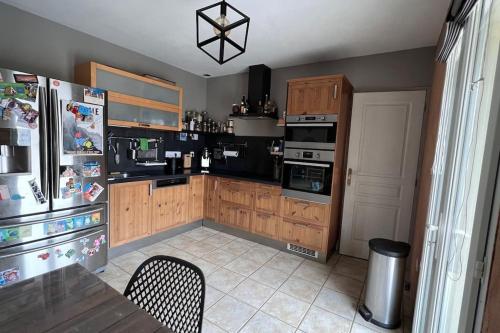 a kitchen with a refrigerator and a table with chairs at Maison entre lac et montagne in Prunières