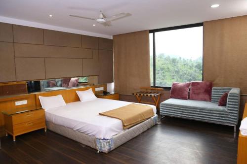 een slaapkamer met een bed, een bank en een stoel bij A Luxury Stay in S9 Hotel and Restaurant Near Ambaji in Ambaji
