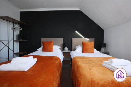 a bedroom with two beds with orange and white sheets at Palmers Leaze, Comfortable house close to Aztec West in Bristol