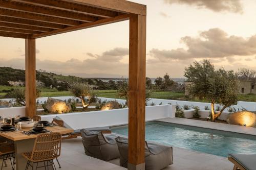 un patio al aire libre con mesa y sillas y una piscina en P square Luxury villas Naxos, en Kastraki Naxou