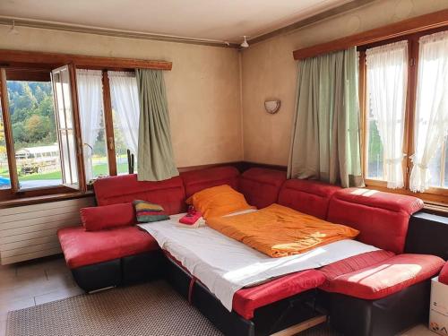 a red couch sitting in a room with windows at Aufschnaufhof in Diemtigen