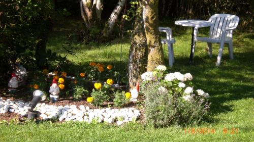 a garden with a table and a chair and flowers at Auberge De L'Atre in Quarré-les-Tombes