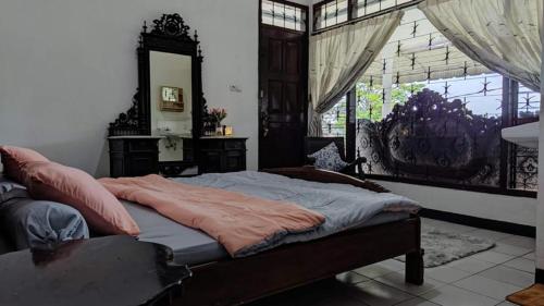 a bedroom with a bed with a mirror and a window at Kalia Cottage in Batu