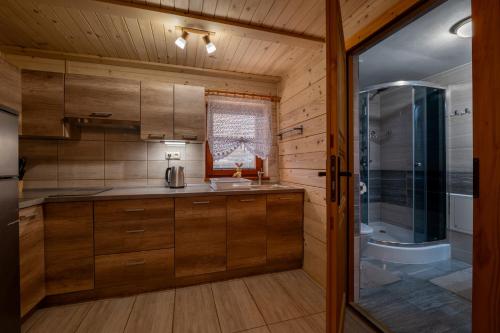 a kitchen with wooden cabinets and a sink and a shower at Drevenička Vodníček in Liptovský Trnovec