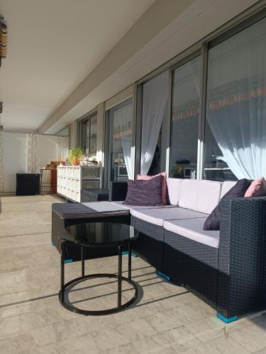 - un canapé et une table dans une chambre avec fenêtres dans l'établissement ARA 40m2 Classé Immense Terrasse 35 m2 Piscine Antibes Juan Parking, à Antibes