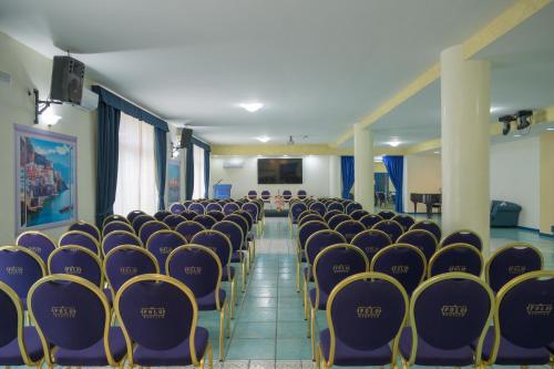 an empty room with purple chairs and a screen at Hotel Centro Congressi Polo Nautico in Salerno