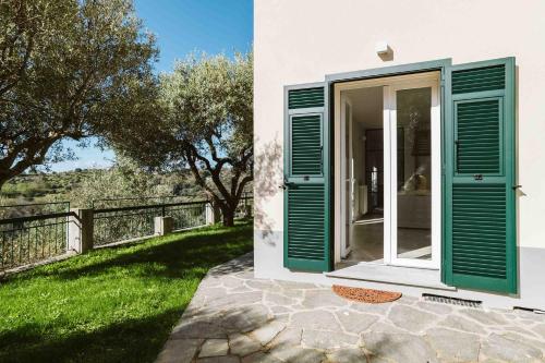 una puerta con persianas verdes en una casa blanca en ABC affittacamere en Celle Ligure