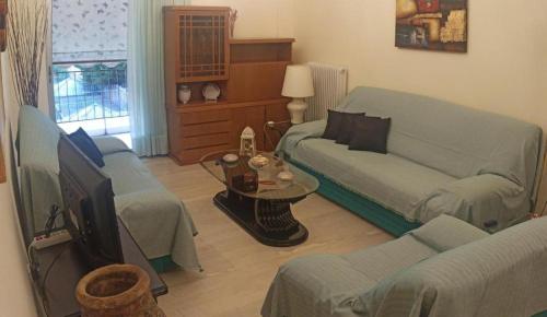 uma sala de estar com um sofá e uma televisão em Comfortable apartment 200 m from the sea em Piraeus
