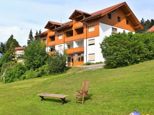 a bench sitting in the grass in front of a building at Holiday home with panoramic view and every convenience spa in Waldkirchen