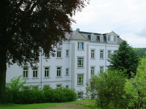 ein weißes Haus auf einem Hügel mit Bäumen in der Unterkunft Alluring Villa in Grunhainichen Borstendorf with Garden in Leubsdorf