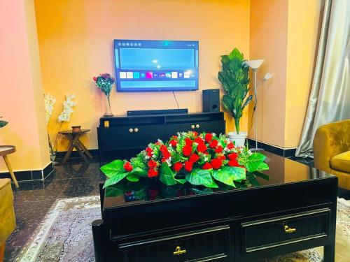een woonkamer met een tv en een tafel met bloemen bij The central Heartbeat Haven Intercity in Dar es Salaam