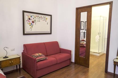 a living room with a red couch and a mirror at La Casa del Fabbro in Troina