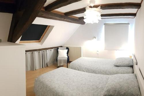 Cette chambre mansardée comprend 2 lits et une télévision. dans l'établissement Les Toits de Colmar, à Colmar