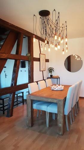 une table à manger avec des chaises blanches et un lustre dans l'établissement Les Toits de Colmar, à Colmar
