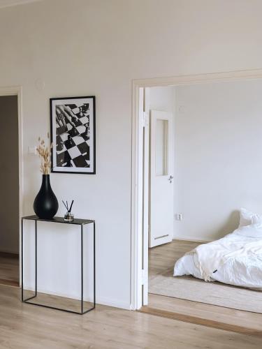Un dormitorio con una cama y una mesa con un jarrón. en Valoisa huoneisto, loistavalla sijainnilla!, en Helsinki