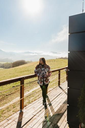 a woman walking on a wooden boardwalk in a field at Sidehill - zážitkové ubytovanie v prírode in Martin
