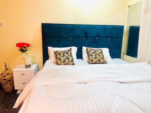 un grande letto con testiera blu e due cuscini di Downtown Dreamspace City - 3 bedrooms a Dar es Salaam