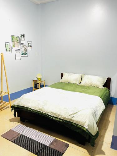 a bedroom with a bed with a green comforter at MOCA MOTEL in Cao Lãnh