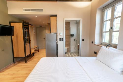 1 dormitorio con 1 cama blanca y nevera en Kraka Apartments, en Leonidio