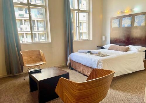 a bedroom with a large bed and two windows at Mapungubwe Apartments in Johannesburg