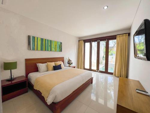 a bedroom with a large bed and a large window at Apple Villas & Apartments in Kerobokan