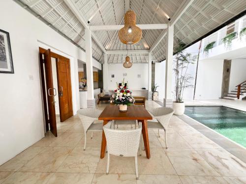 a dining room with a table and chairs and a pool at Apple Villas & Apartments in Kerobokan