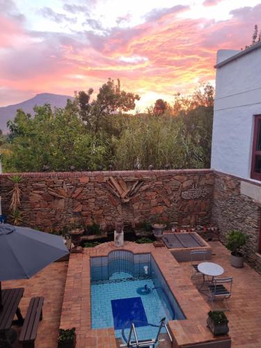 a backyard with a swimming pool and a stone wall at Barrydale Karoo - BOUTIQUE HOTEL in Barrydale
