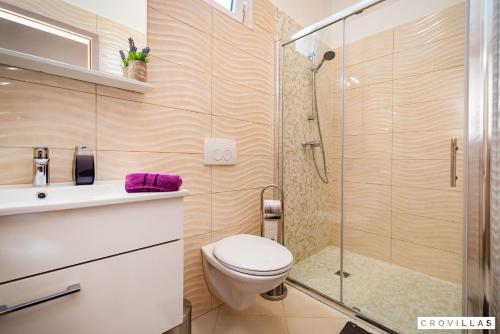 La salle de bains est pourvue de toilettes et d'une douche en verre. dans l'établissement Luce, à Zadar