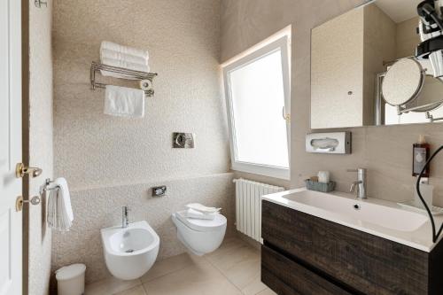a bathroom with a toilet and a sink and a mirror at La Terrazza Sulla Rupe Relais in Ostuni