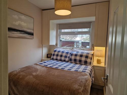 Habitación pequeña con cama y ventana en 28 Broadside Holiday Chalet near Broads & Beaches en Stalham