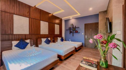 a hotel room with two beds and a vase of flowers at The Luxury in Siem Reap