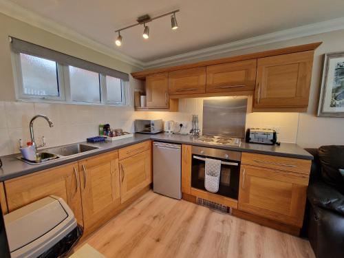 una cocina con armarios de madera y electrodomésticos de acero inoxidable en 28 Broadside Holiday Chalet near Broads & Beaches en Stalham