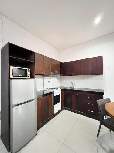 a kitchen with wooden cabinets and a stainless steel refrigerator at Apple Villas & Apartments in Kerobokan