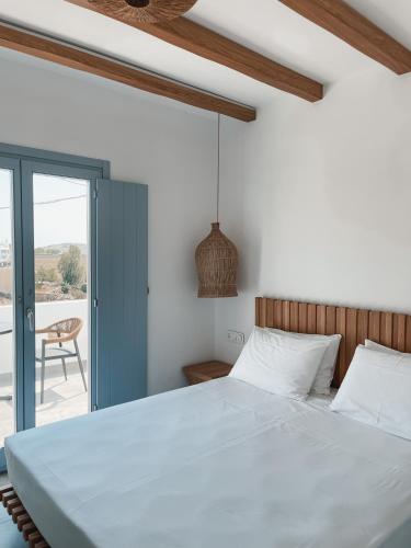 a bedroom with a large white bed and a sliding glass door at SOHOROS suites in Schinoussa