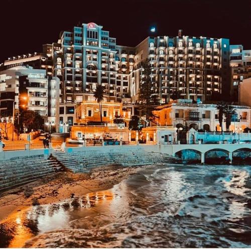 uitzicht op een stad in de nacht met gebouwen bij Brand New St. Julian's Luxury Apartment - Wish Malta in St Julian's