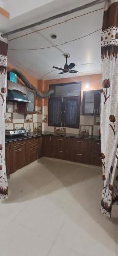 Il comprend une cuisine avec des placards en bois et un ventilateur de plafond. dans l'établissement Cozy Retreat, à Haridwar