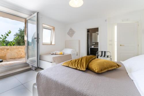 a white bedroom with a bed with a yellow pillow at La Terrazza Sulla Rupe Relais in Ostuni