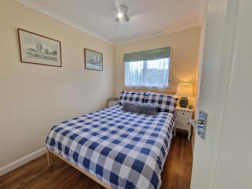 a small bedroom with a blue and white checkered bed at 169 Broadside Holiday Chalet near Broads & Beaches in Stalham