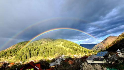 a rainbow over a town with a mountain at Vila Giulia Voineasa in Voineasa