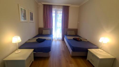 two beds in a room with two lamps and a window at СОЗОПОЛ - MORE SUN СОЗОПОЛИС 2 Б in Burgas City