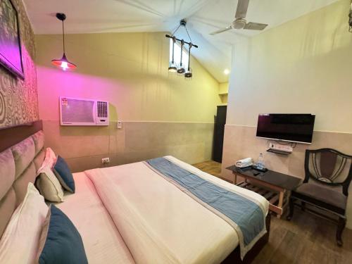 a bedroom with a bed and a chair and a tv at Hotel Height's - Kalka ji in New Delhi