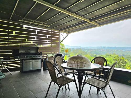 a patio with a table and chairs and a grill at Villa Montaview Puncak (Mountain View Cottage) in Gadok 1