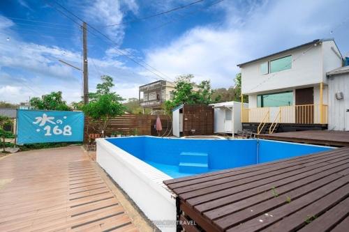 a house with a blue swimming pool in front of a house at Water 168 Homestay in Xiaoliuqiu