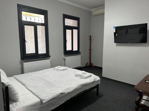 a white room with a bed and two windows at Hostel Premium Tashkent in Tashkent