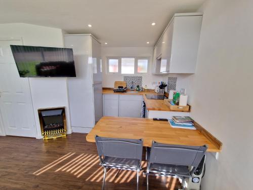 een keuken met een houten tafel en een tv aan de muur bij 67 Broadside Holiday Chalet near Broads & Beaches in Stalham